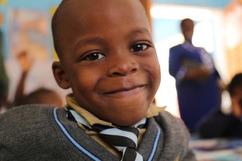 A school children smiles at the camera. Avondale Infant School, Zimbabwe